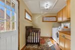 Crib in larger laundry room, entrance to fenced backyard